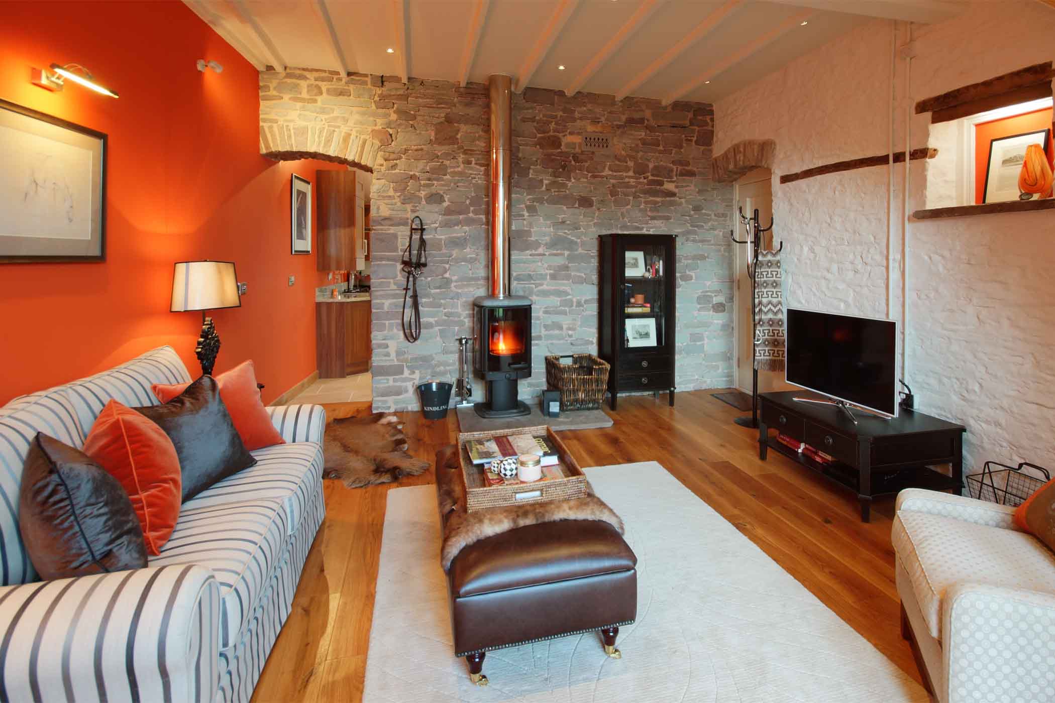 Sitting room at The Coach with vaulted ceilings, exposed stone and wood-burning stove