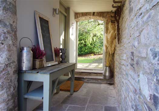 Stone-flagged porch entrance at The Dairy with rustic bench and country details