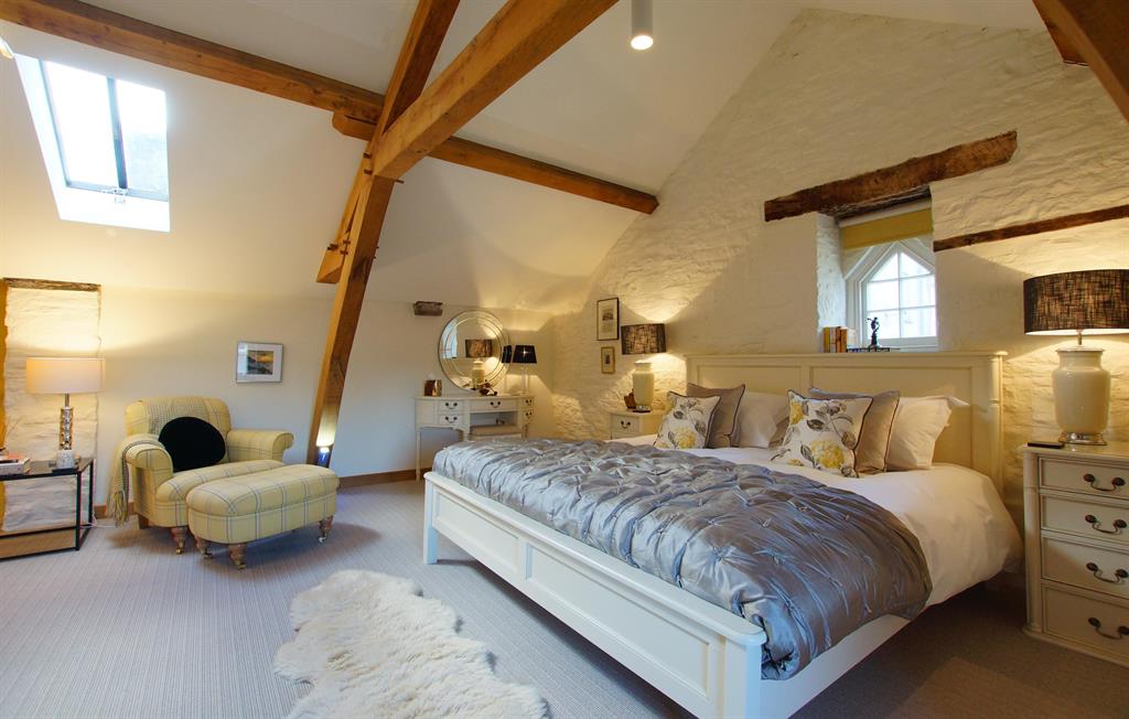 Elegant bedroom at The Laundry with vaulted beamed ceiling, exposed timber trusses and stone walls